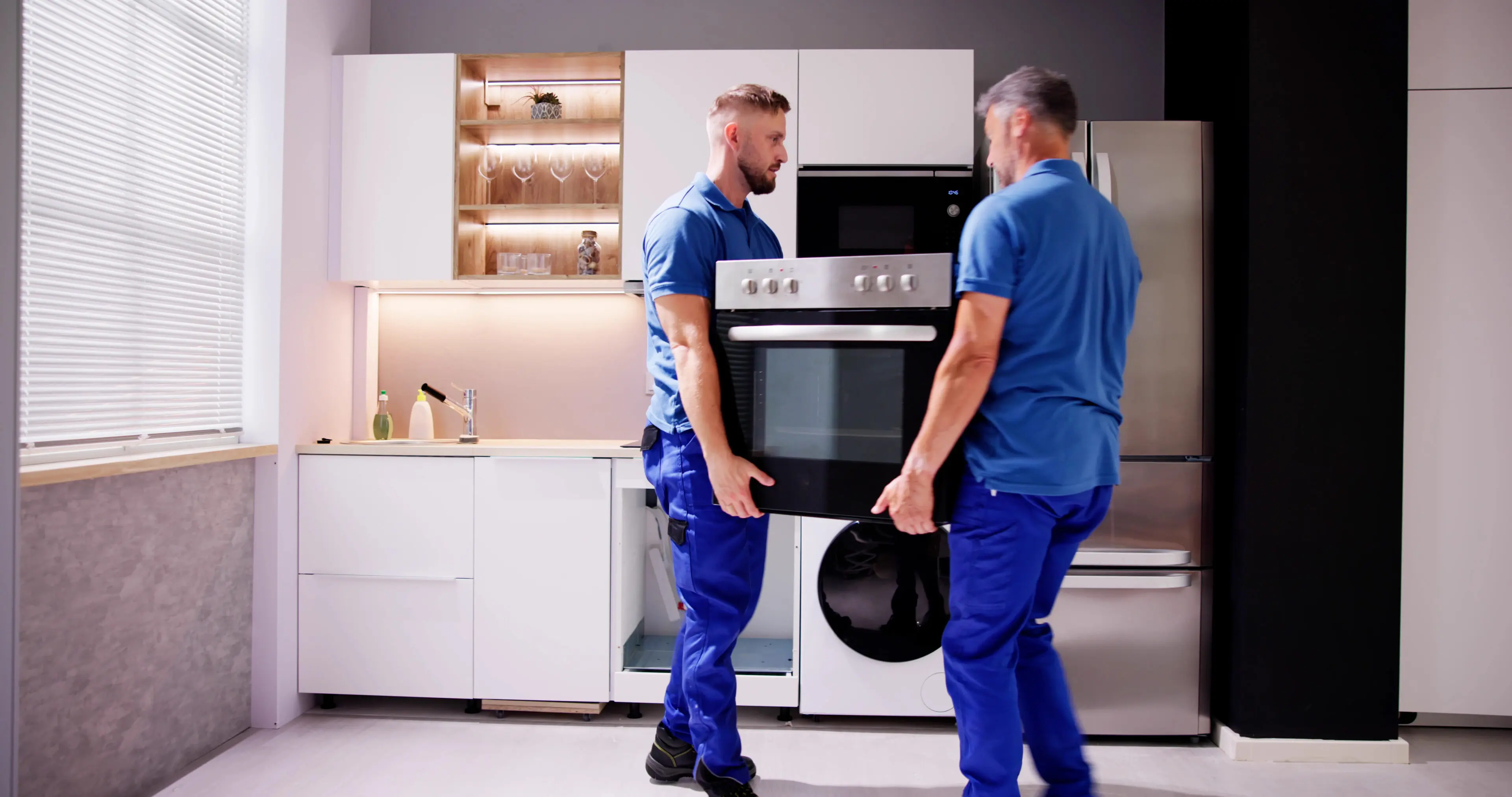 Appliance Delivery And Repair Two men in blue shirts carrying a black oven.