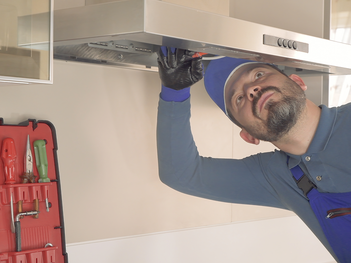 A man in blue shirt and red gloves fixing a ceiling.