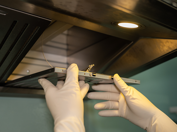 A person in white gloves holding a metal object.