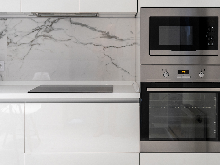 A kitchen with white cabinets and marble countertops.