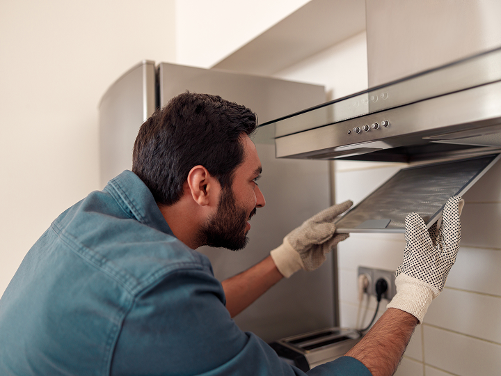 A man in gloves is fixing the oven.