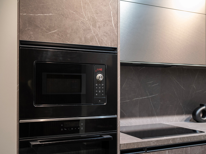 A black microwave oven sitting in the middle of a kitchen.