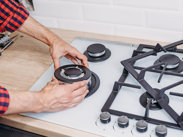 A person is putting the gas burner on the stove.