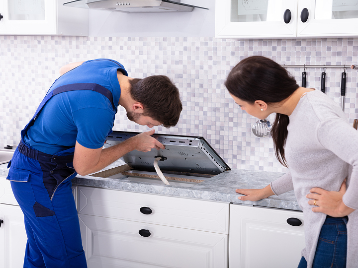 A man and woman looking at an oven in the kitchen.