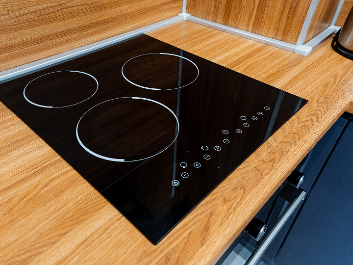 A black stove top sitting on top of wooden counter.
