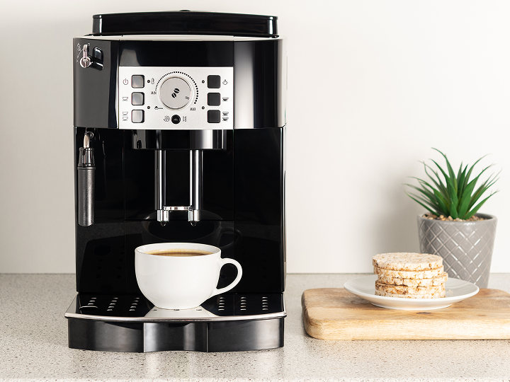 A coffee machine with a cup of coffee on the side.