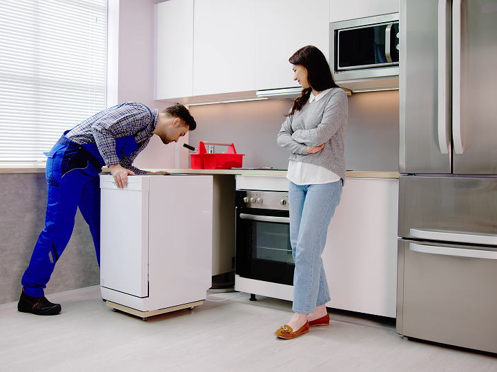 A man and woman in the kitchen looking at each other.