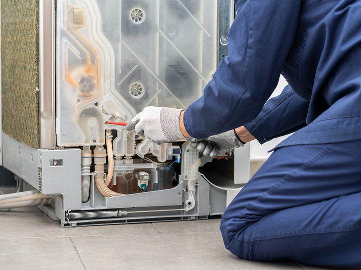 image 9 A person in blue work clothes working on an appliance.