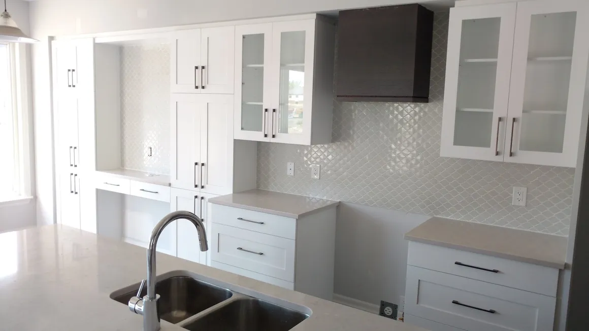rs=w_1160,h_653 A kitchen with white cabinets and black counter tops.